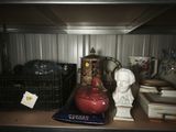 a red vase on a shelf next to other items