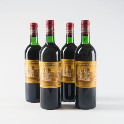 quatre bouteilles de vin sont alignées sur une surface blanche
