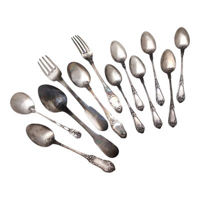 un grand nombre de cuillères et de fourchettes en argent sur une surface blanche