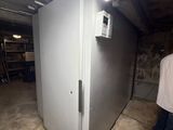 a man standing next to a white refrigerator in a room