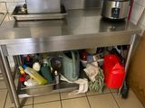 une table de travail en acier inoxydable sur laquelle sont posées une casserole et une poêle