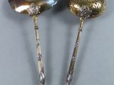two silver spoons with a shell on top of them sitting on a table