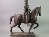 bronze statue of a man riding a horse on a wooden base