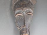 un masque en bois accroché au mur d'une pièce