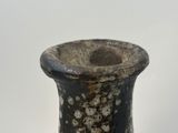 a black and white vase sitting on a white surface