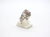an image of a ring with a purple stone on top of a stand