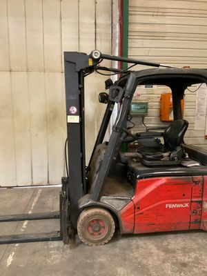 un chariot élévateur rouge garé dans un garage à côté d'un immeuble