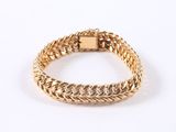 a close up of a gold bracelet on a white background