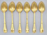 six gold spoons and a spoon with a handle on a table