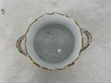 a white cup with a gold rim sitting on a white surface