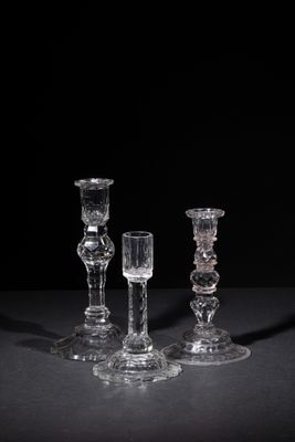 three clear glass candlesticks sitting on a black surface