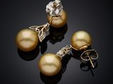 three golden pearl earrings and a pair of earrings on a black surface