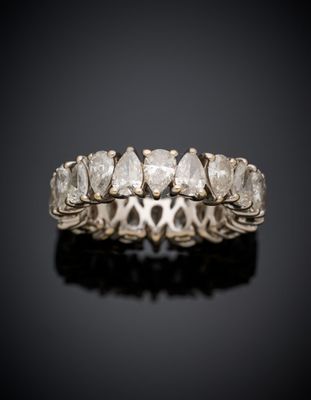 a white gold ring with five pear shaped diamonds on a black surface