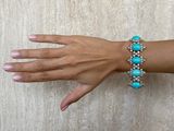 someone is wearing a bracelet with turquoise stones on it
