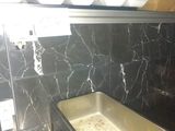 a sink in the middle of a kitchen with a black marble counter top