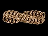 gros plan d'un bracelet en or sur fond noir