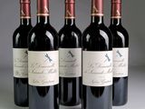 quatre bouteilles de vin rouge sont alignées sur une table