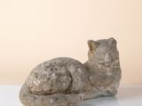 sculpture représentant un chat assis sur une surface blanche, sur fond beige