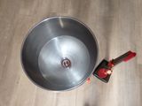 a metal bowl with a red handle on a wooden floor
