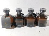 quatre flacons de parfum sont alignés sur une surface blanche