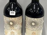 two bottles of red wine sitting next to each other on a table