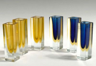four different colored vases in a row on a white surface