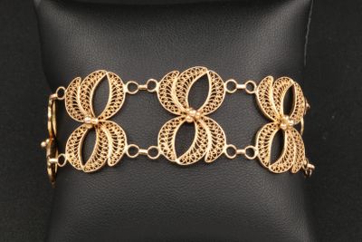 un bracelet plaqué or posé sur un coussin noir