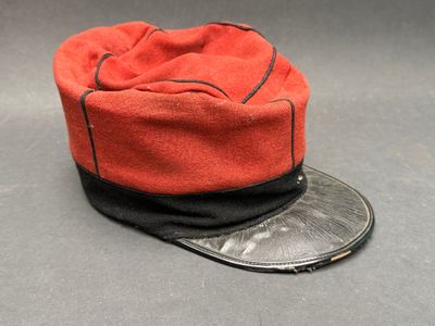 un chapeau orange orné d'un ruban noir et d'une pièce de monnaie, posé sur une surface grise