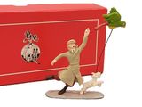 une figurine représentant un homme avec un chien en laisse devant une boîte rouge