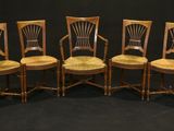 six wooden chairs are lined up against a black backdrop