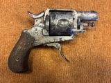 un vieux revolver avec une poignée en bois sur une surface en bois