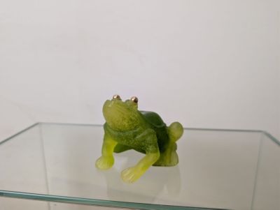 une figurine de grenouille verte posée sur une table en verre