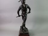 bronze statue of a man with a sword on a wooden base