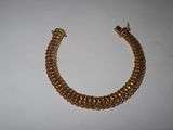 a close up of a gold chain bracelet on a white surface