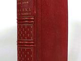 an old red book sitting on top of a white surface
