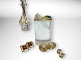 a glass of water with a gold cuff and a pair of cuff rings