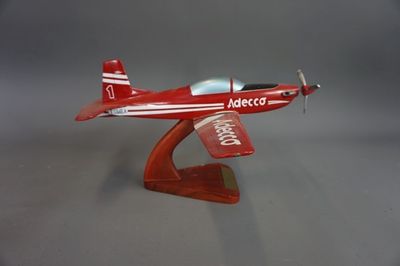 une petite maquette d'avion rouge posée sur un socle en bois