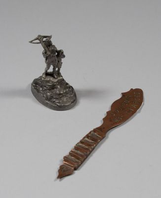 a silver statue of a man on a rock next to a knife