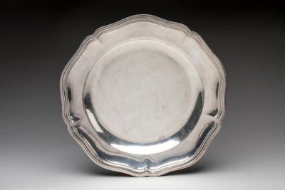 a silver plate on a white surface with a black background
