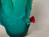 a green vase that has a red flower in it