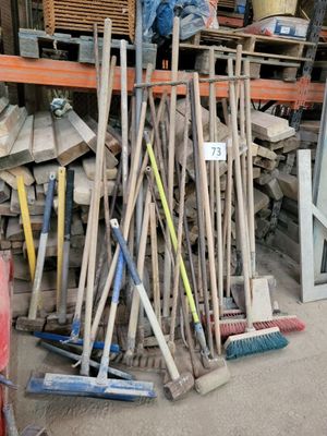 a pile of brooms and broom brushes in a garage