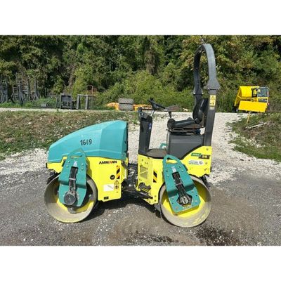 a yellow and blue road roller sitting on top of a gravel road