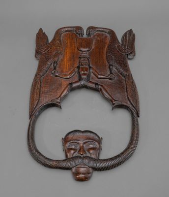 une image représentant un heurtoir de porte en bois orné d'un visage d'homme