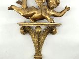 a close up of a gold statue of a cupid on a shelf