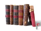 several old books are lined up in a row on a white surface