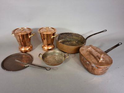 un grand nombre de casseroles et de poêles en cuivre posées sur une table