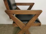 une chaise en bois avec une assise en cuir noir, dans un coin de la pièce