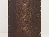 an old book sitting on top of a white table next to a white wall