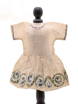 une vieille robe posée sur un pied de mannequin, devant un fond blanc