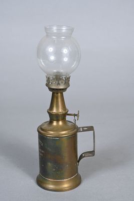 an old fashioned oil lamp with a glass on top of it